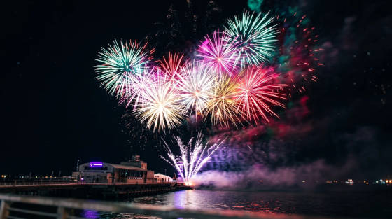 Colourful fireworks bursting over a pier at night
