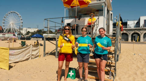 Three lifeguards holding first aid kits at Bournemouth Beach