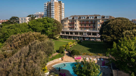 Lush garden with a swimming pool and hotel buildings in Bournemouth