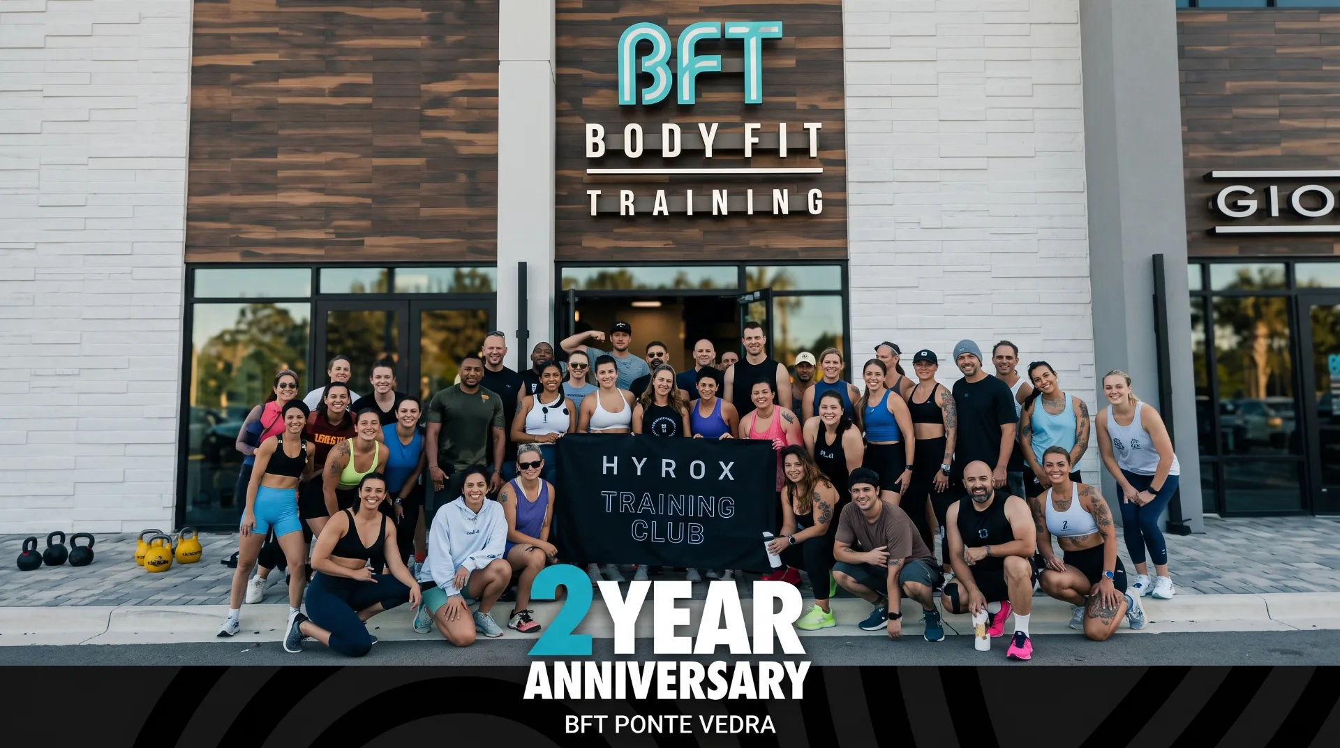 Group of fitness enthusiasts posing outside BodyFit Training with a HYROX Training Club banner