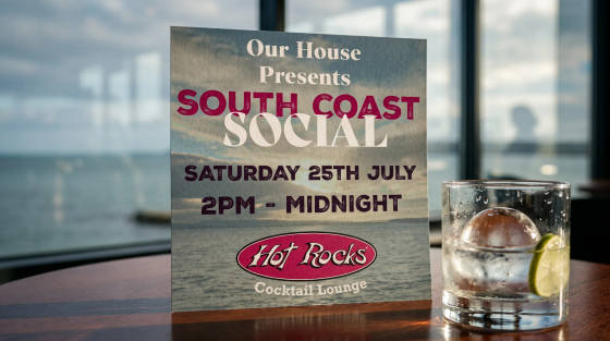 Event sign for South Coast Social with a drink on a table