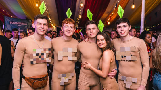 Five friends in beige bodysuits with cardboard and green props