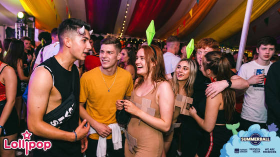 Group of young adults socialising at a summer ball with colourful decorations