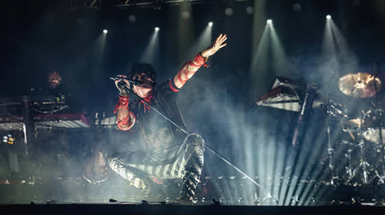 A performer singing on stage with dramatic lighting and smoke