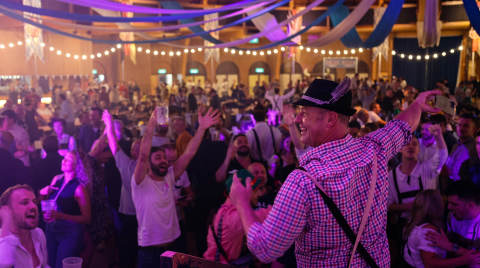 A crowded hall with people celebrating and a performer in traditional attire