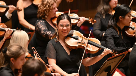 Smiling female violinist playing in an orchestra