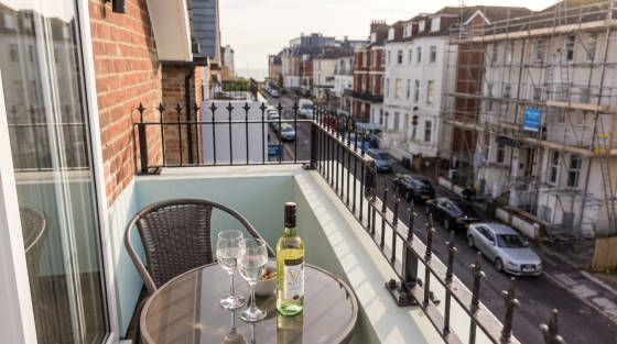 Table with wine bottle and glasses on a balcony overlooking a street