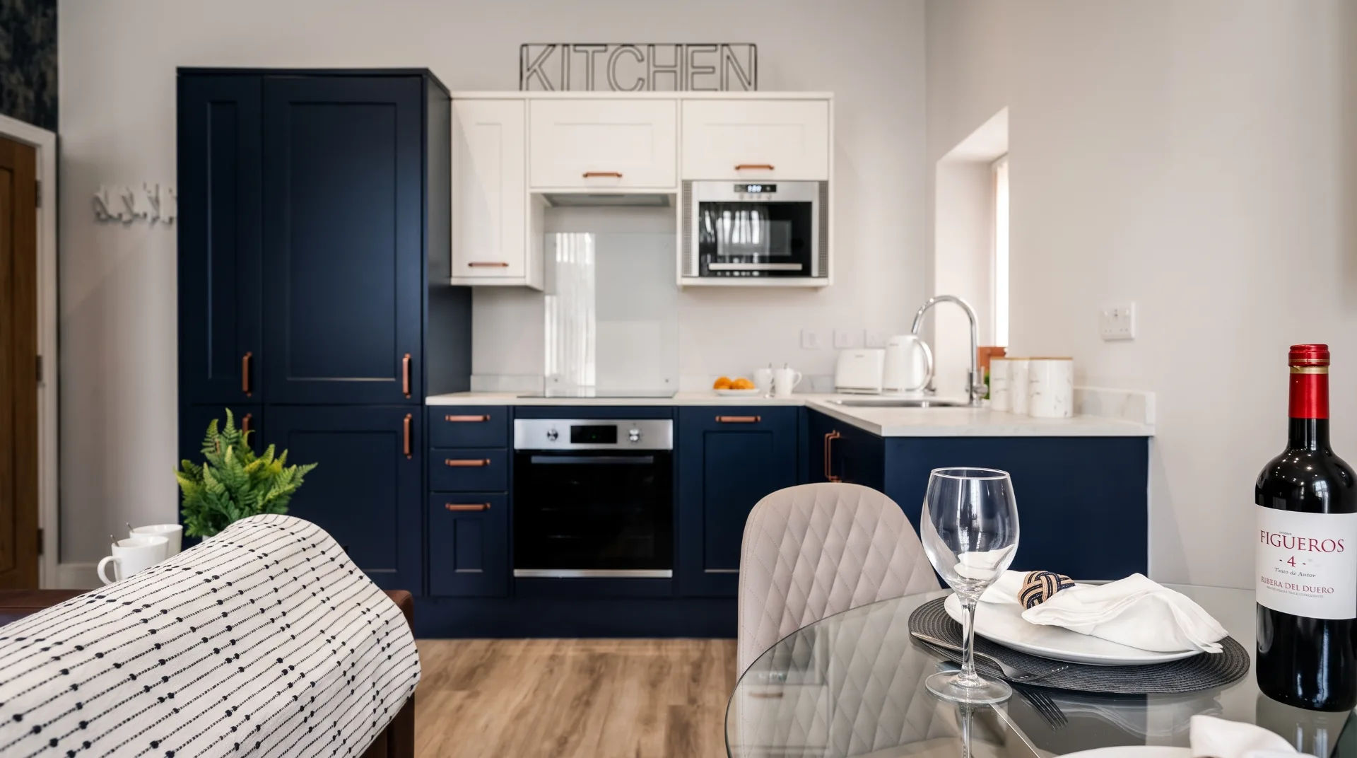 Modern kitchen with navy cabinets, white countertops, and dining table set with wine and plates
