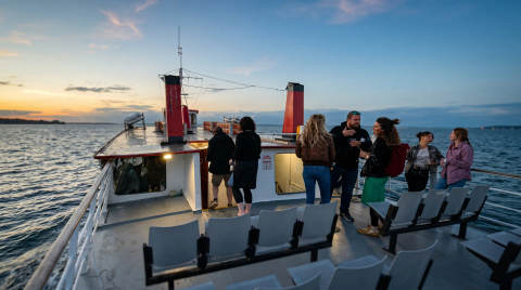 Group of people chatting on a boat with sunset in the background