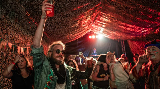 People celebrating in a tent with colourful lighting and drinks