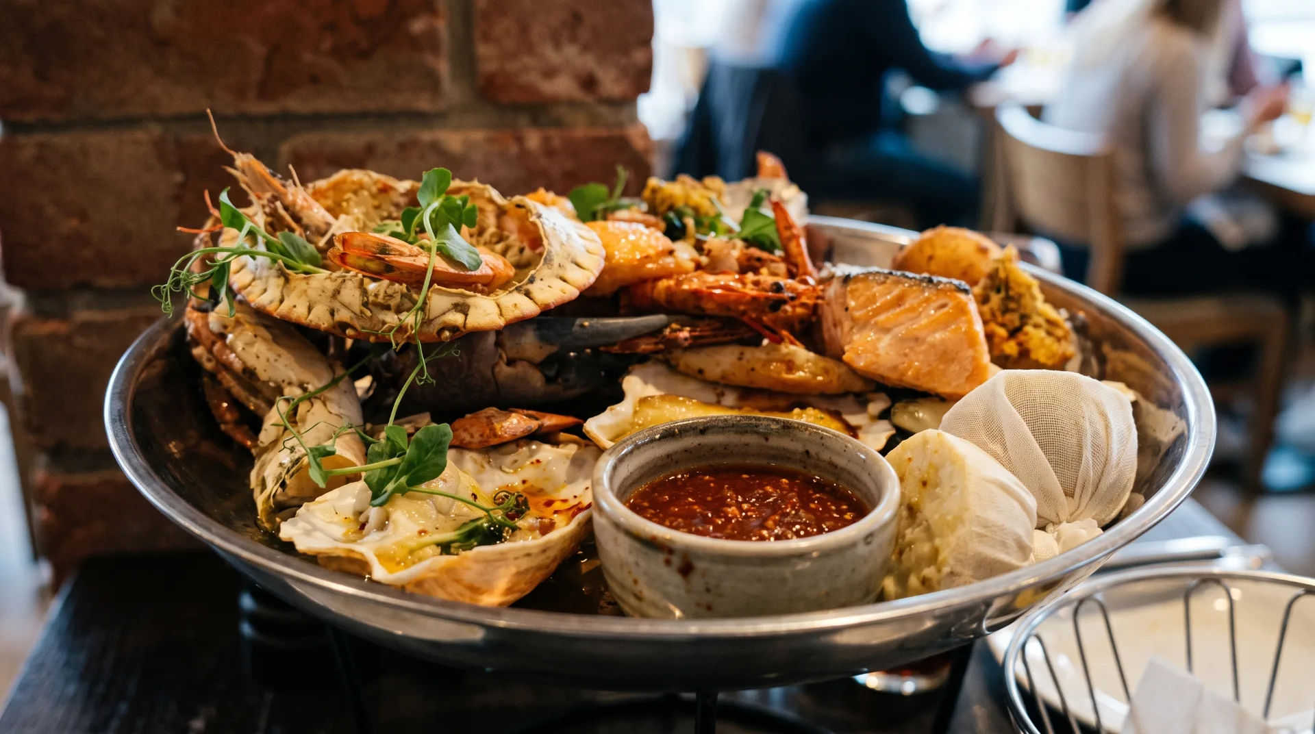 A large platter filled with various seafood including prawns, crab, and salmon, with a bowl of sauce in the centre.