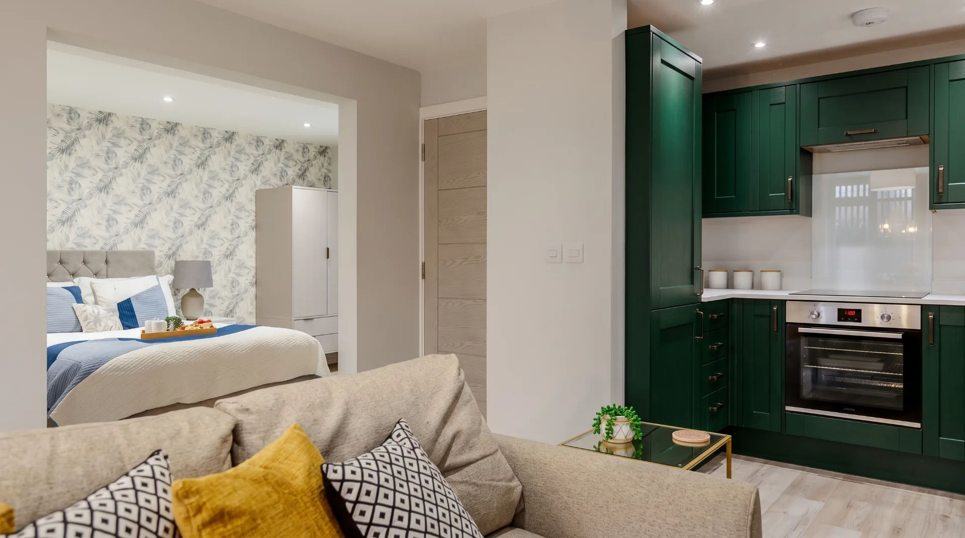 Stylish living space featuring a modern kitchen and a bedroom area with decorative wallpaper