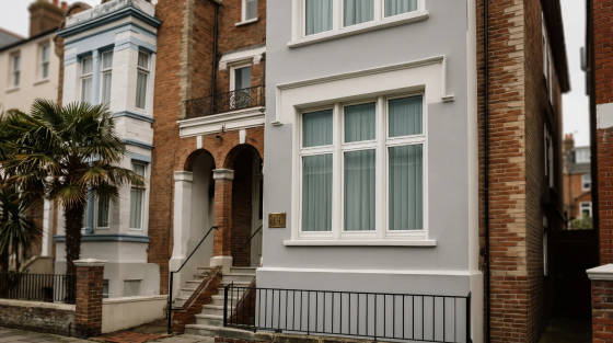 Grey residential building with palm tree and brick details