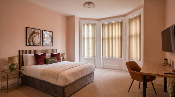 Modern bedroom with a bed, artwork, and desk