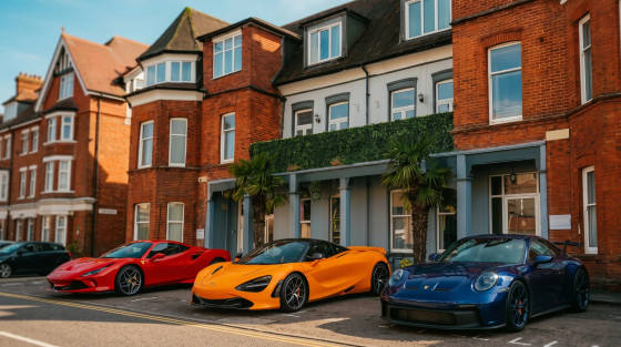 Three luxury sports cars in front of a red brick building