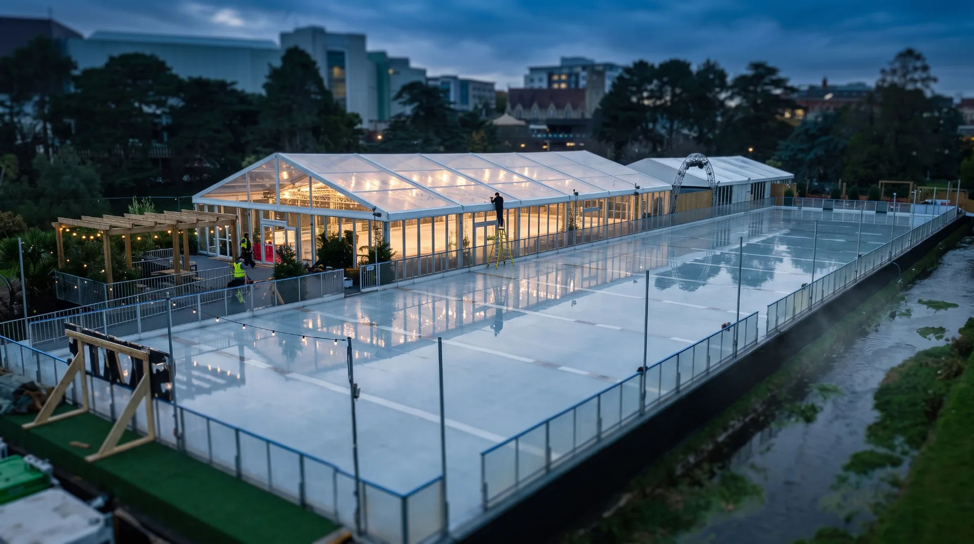 Open-air ice rink in Lower Gardens with a clear roofed pavilion and workers preparing the area