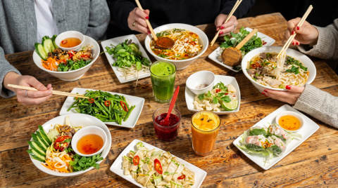 A selection of Asian dishes with chopsticks on a wooden table