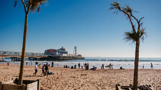 Beachgoers on Bournemouth beach with the pier in the background