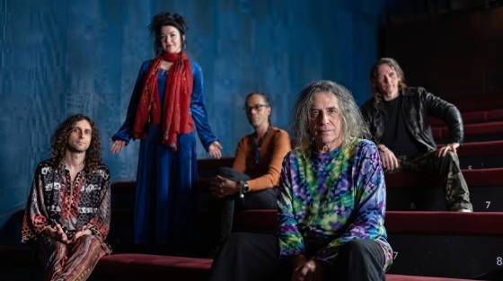 Five members of a musical group seated in a theatre
