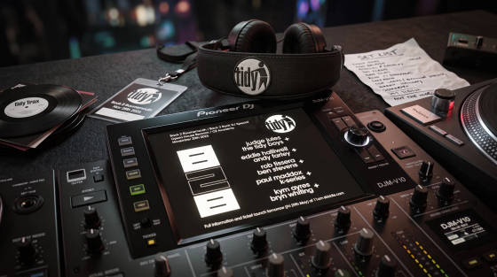 DJ mixer, vinyl records, headphones and set list on a table