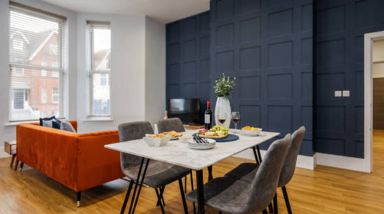 Dining table with food and drinks, orange sofa in background
