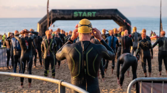 Triathletes in wetsuits preparing for a race at the beach