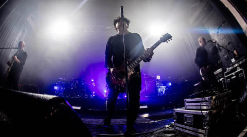 Band performing on stage with dramatic lighting and smoke