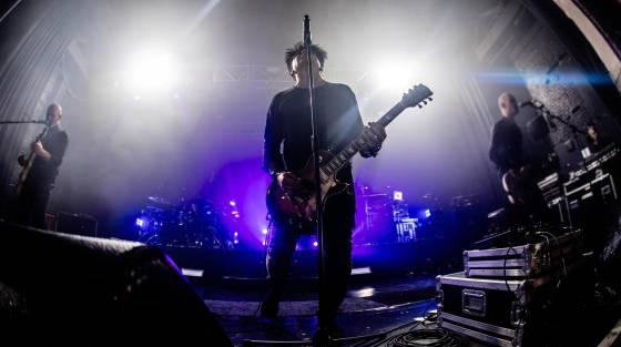 Band performing on stage with dramatic lighting and smoke