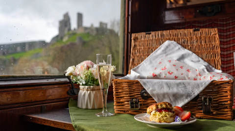 A picnic basket, scones with cream and strawberries, and a view of Corfe Castle