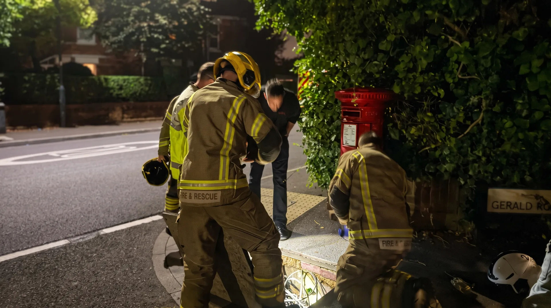 Emergency responders examining a manhole near a post box in Bournemouth at night