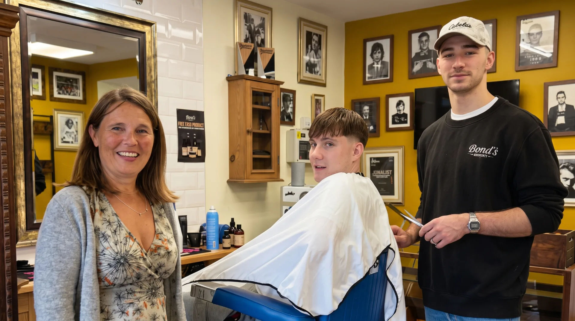 Vikki Slade MP smiles alongside a young man in a barber chair and a barber holding scissors
