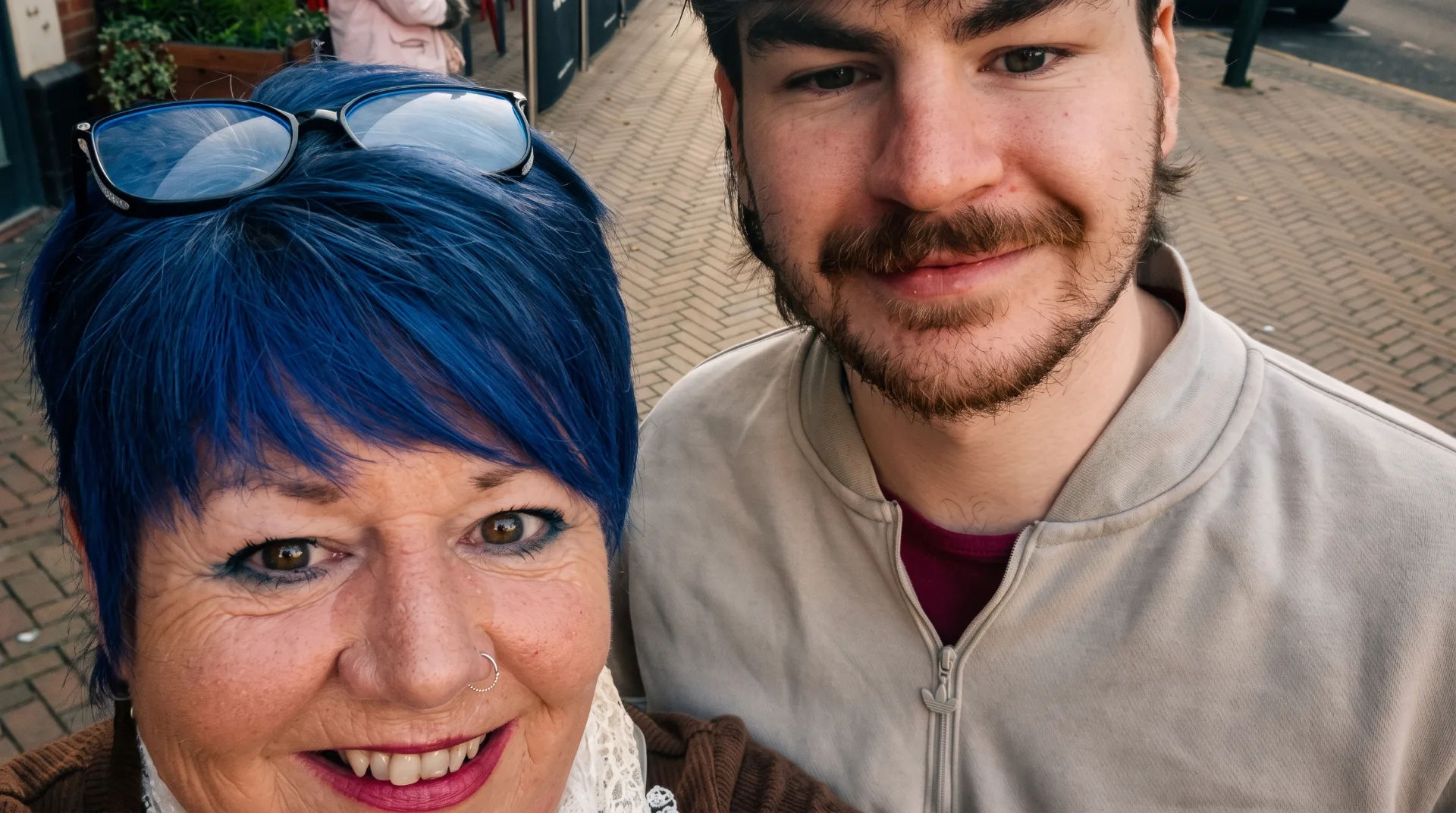 A smiling woman with blue hair and a man with a beard pose together on a street in Bournemouth.