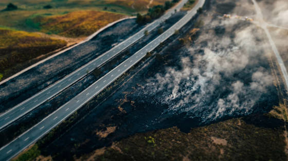 Aerial view of burnt land next to a dual carriageway