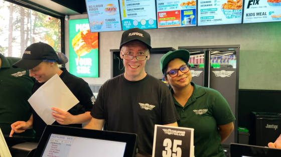 Three staff members smiling at the counter of Wingstop restaurant
