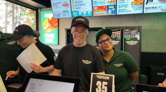 Three staff members at Wingstop restaurant smiling at the counter
