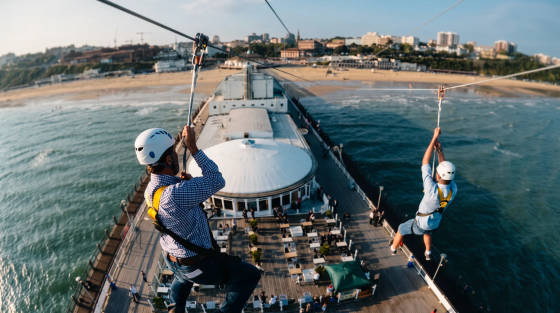 Two people zip lining from Bournemouth Pier over the sea