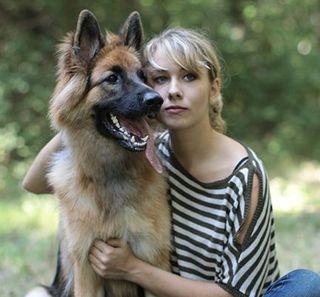 Une femme à côté d'un Berger Allemand en pleine nature