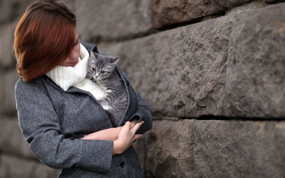 Une femme portant son chaton entre les bras