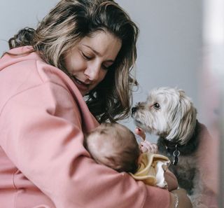 Mère tenant son bébé avec son chien à côté