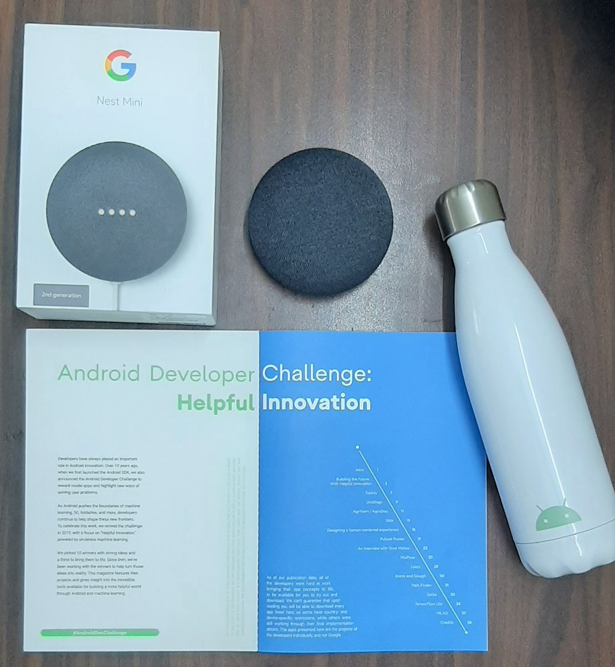 A bottle, Google Nest Mini and the magazine