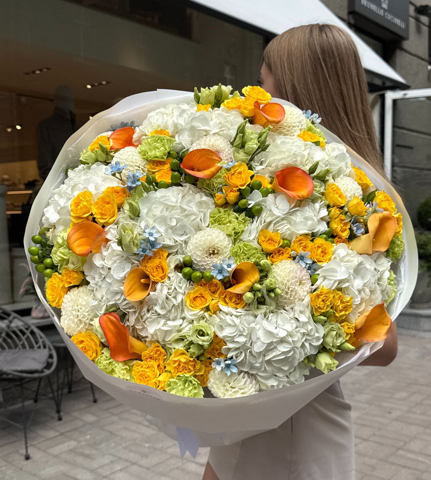A bouquet in a sunny white-and-yellow palette with bright orange accents.