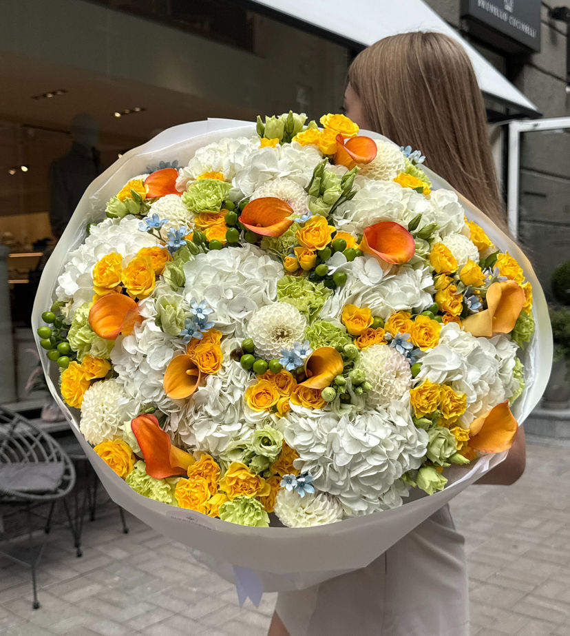 A bouquet in a sunny white-and-yellow palette with bright orange accents.
