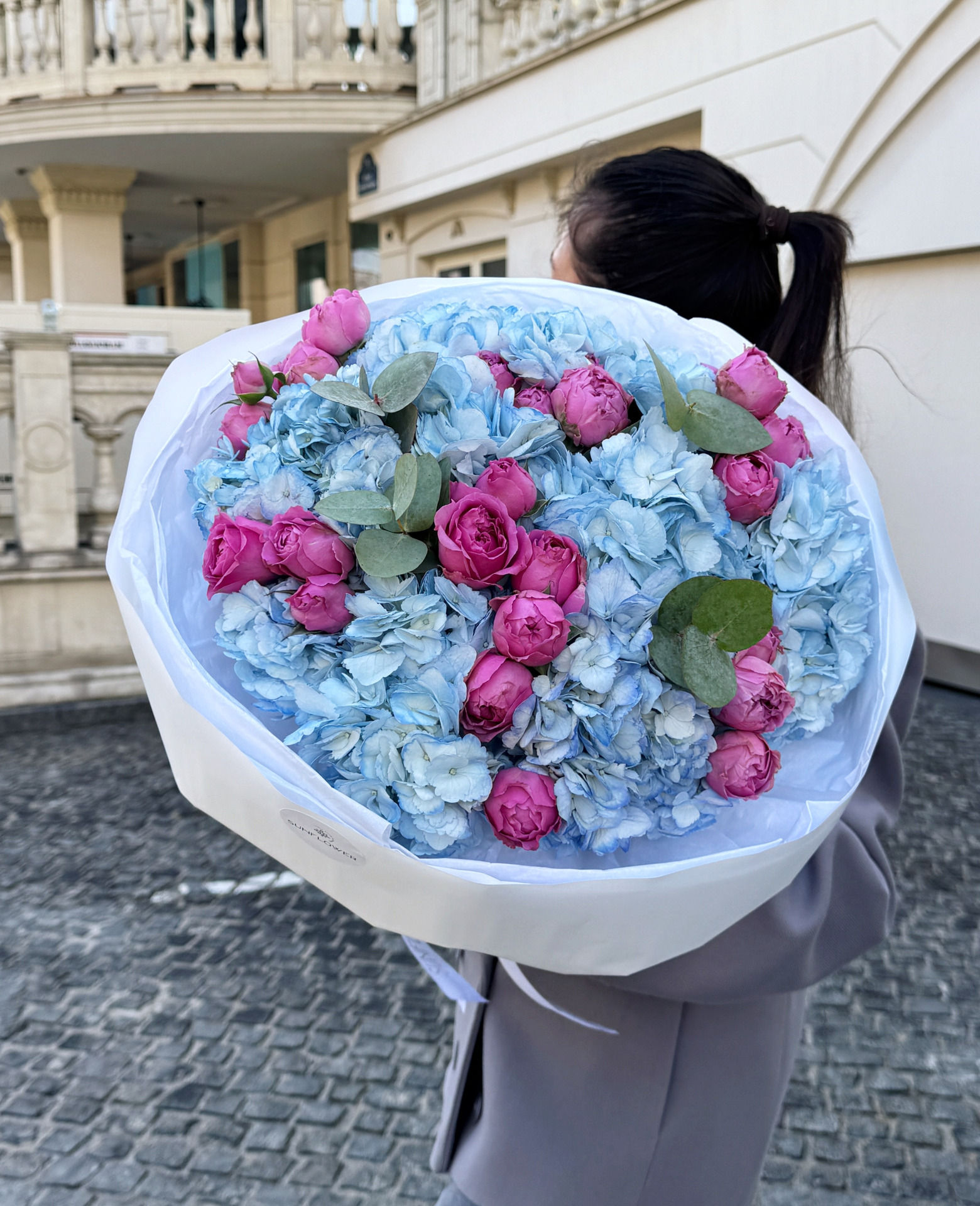 Stylish S-size bouquet in a blue-pink palette with hydrangea, bush roses, and eucalyptus.