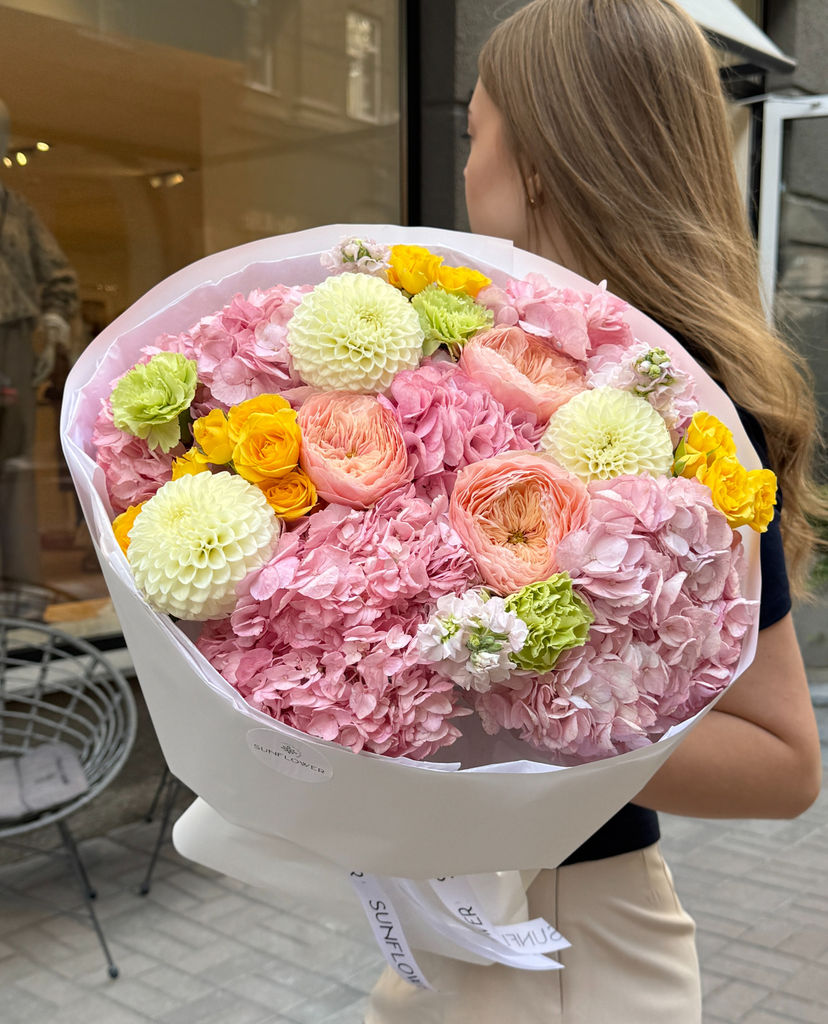 A delicate pink bouquet with warm, sunny accents.