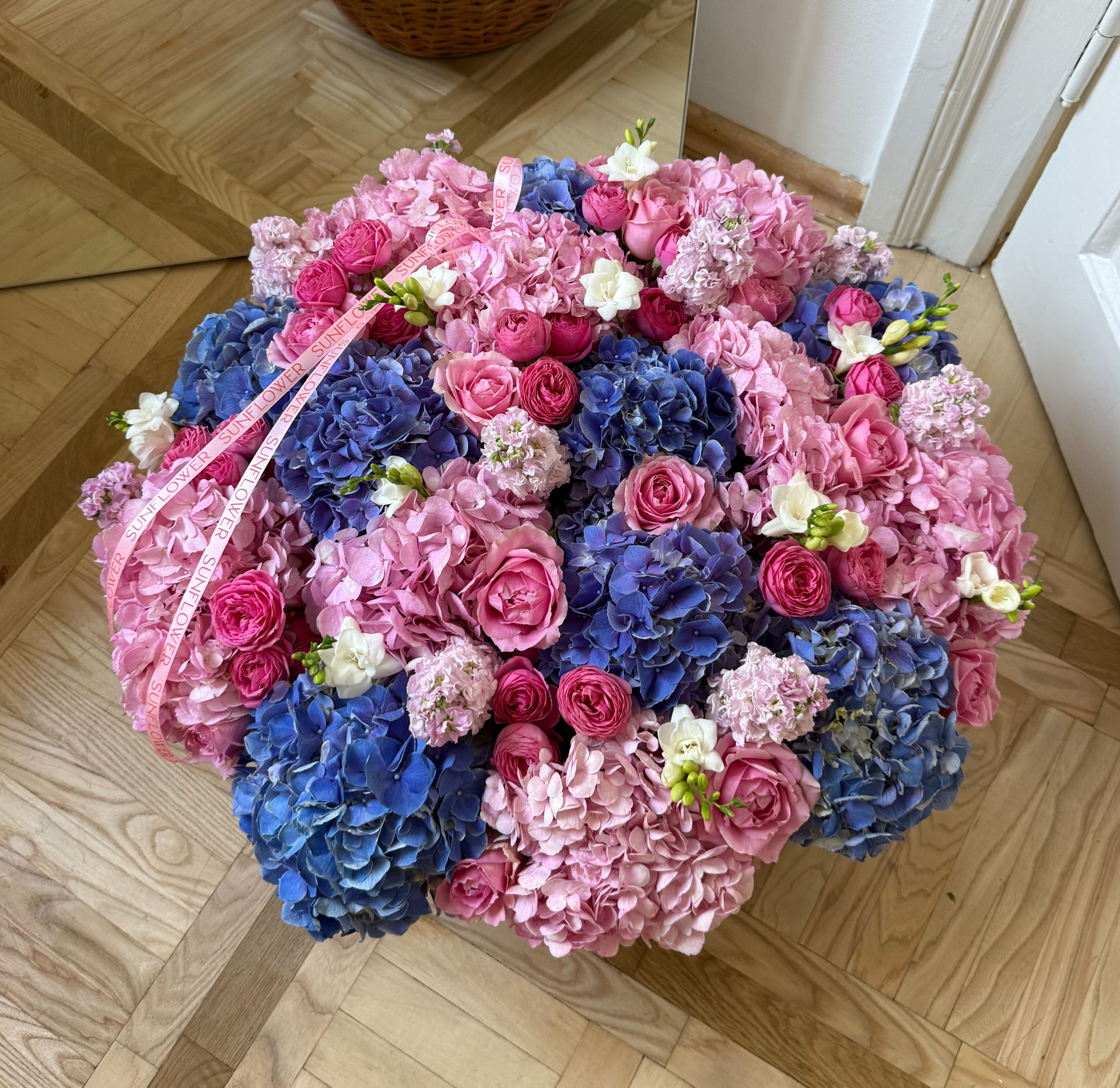Arrangement in a basket with blue hydrangeas and roses
