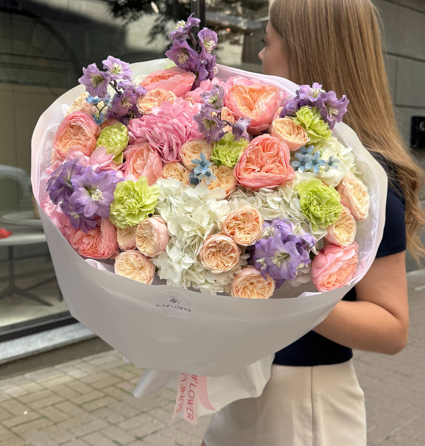 A bouquet in a peach-pink palette with lavender and green accents.