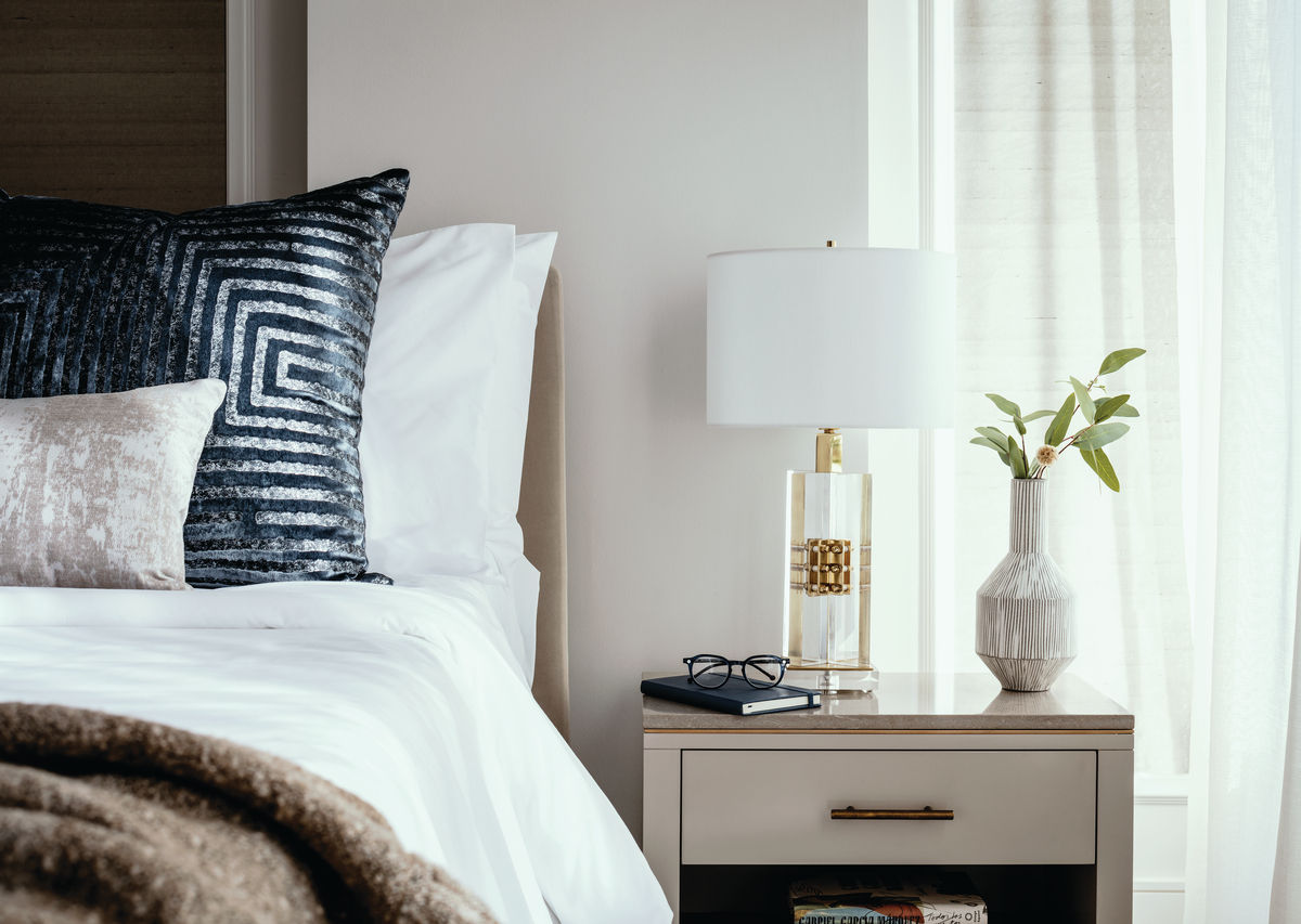 Close up of Cathedral Hill bedroom, showing bed with pillows and bedside table with lamp and reading glasses