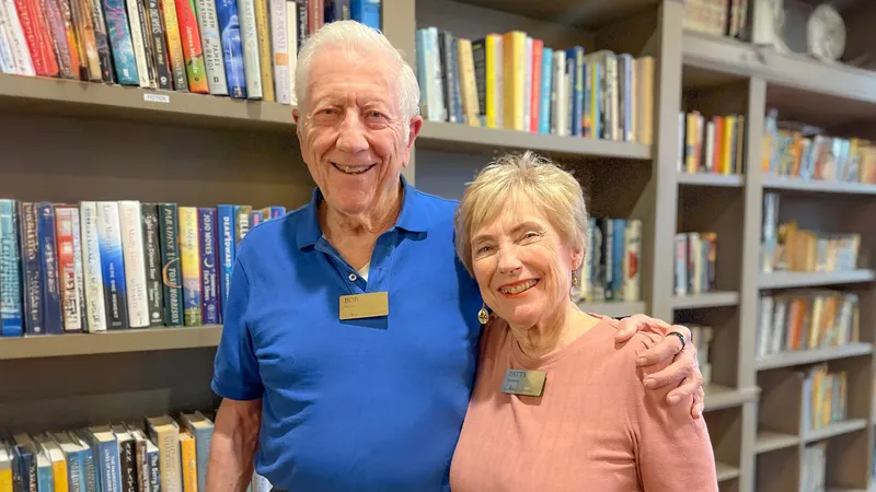 Couple Patty and Bob posing in the library at Atria at the Arboretum