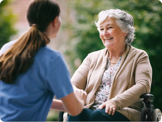 Senior woman smiling while talking to young nurse