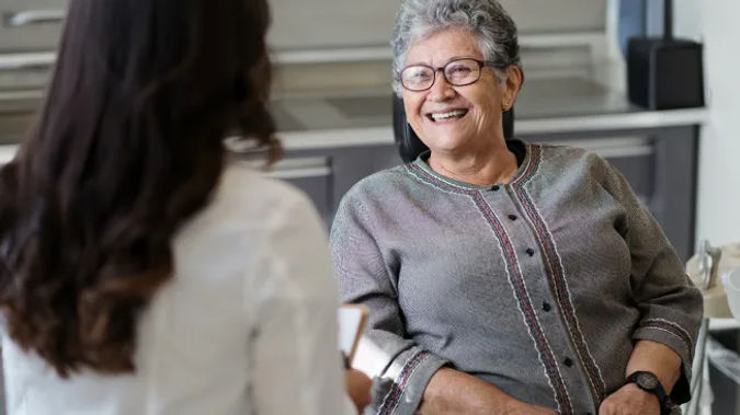 Senior living resident in exam chair with doctor discussing care.